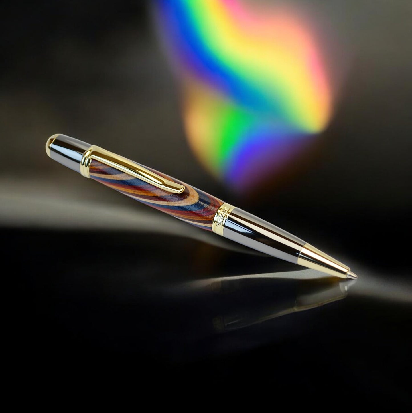 Handcrafted Rainbow Wood ballpoint pen with gold and black titanium trim, handmade in Ireland and presented in a luxury gift box